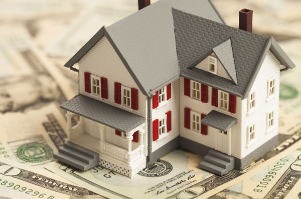 Toy home sitting on money